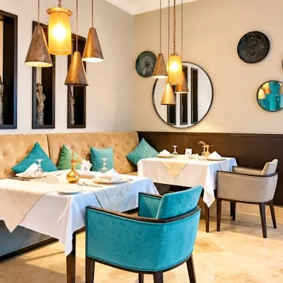 Coin repas intimiste avec fauteuils turquoise et luminaires design au restaurant du Royal Thalassa Monastir.