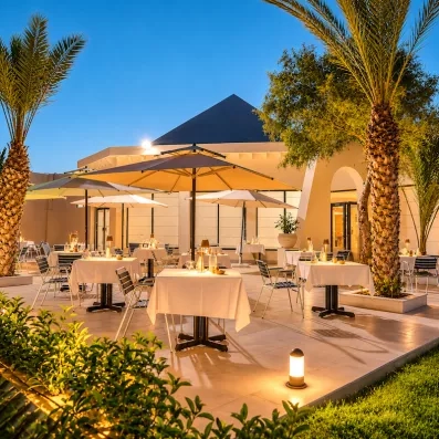 Terrasse de restaurant en plein air avec parasols et palmiers pour un dîner romantique à Djerba.