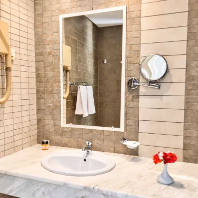 Salle de bain élégante avec vasque en marbre et miroir au César Thalasso à Djerba, Tunisie