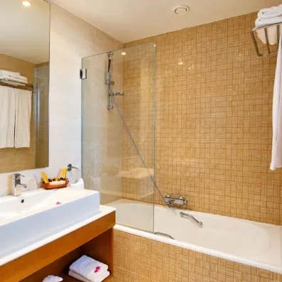 Salle de bain moderne de l'hôtel Helios Beach à Djerba équipée d'une baignoire et de produits d'accueil.