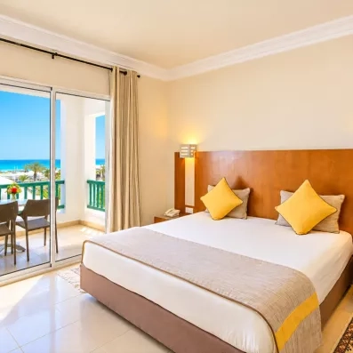 Suite spacieuse et élégante à l'hôtel Helios Beach avec coin salon, grand lit et décoration tunisienne moderne.