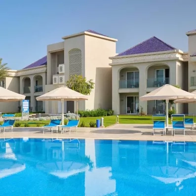 belle ambiance piscine extérieure bleue transat bleu parasol blanc et façade blanc bleu verdure