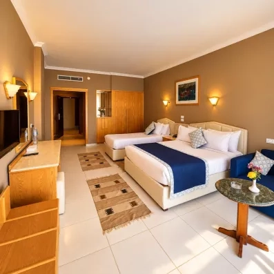 chambre avec 2 lits séparés, tableau décoratif, TV, coiffeuse, tapis, table et fauteuil