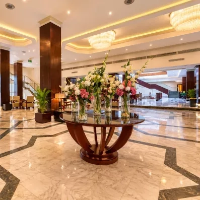 Hall de la réception de l'hôtel, sol en marbre colonnes en bois, table de décoration centrale avec des fleurs
