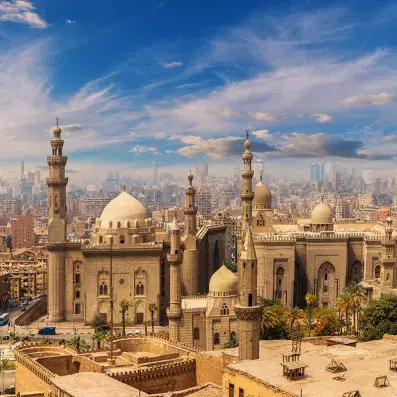Panorama du Caire avec mosquées historiques et skyline moderne, capitale animée de l’Égypte sous ciel lumineux.
