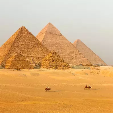 Pyramides de Gizeh au Caire, merveilles de l’Antiquité dans le désert égyptien avec dromadaires au premier plan