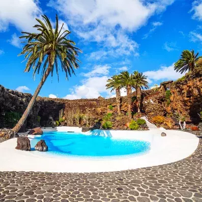Piscine naturelle de Jameos del Agua à Lanzarote, oasis aménagée dans un tunnel de lave avec palmiers et roches volcaniques.