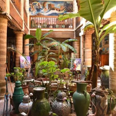 Patio de galerie d’art à Essaouira, plantes exotiques, céramiques marocaines et architecture traditionnelle de kasbah.