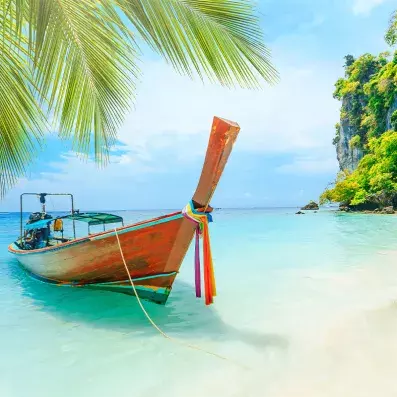 barque en bois traditionnelle thailandaise sur la mer turquoise, palmier en premier plan