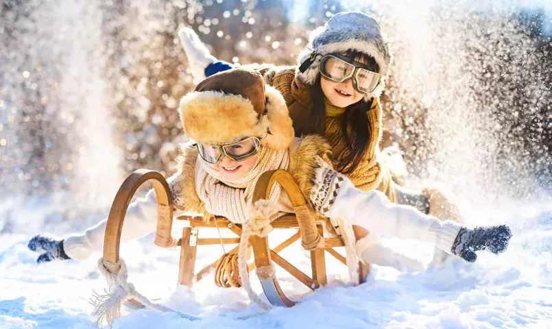 Activités d’hiver en Finlande avec enfants : luge, jeux dans la neige et forêt boréale, vacances famille en Laponie