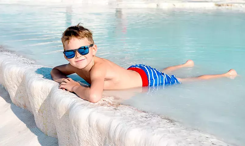 enfant avec des lunettes de soleil se  baignant dans une vasque de calcaire en Turquie à Pamukkale