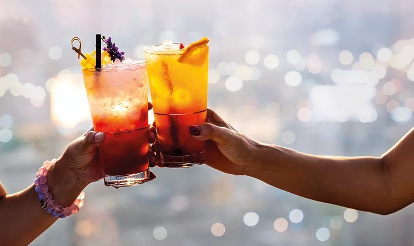 2 personnes tenant un cocktail en bord de mer