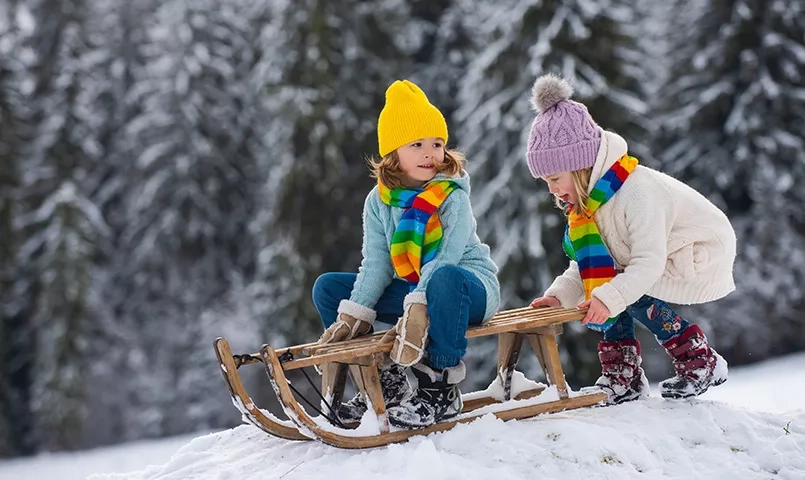 Deux enfant avec des bonnets faisant de la luge