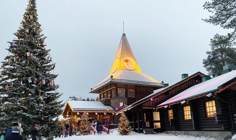 La maison du père Noël avec un sapin illuminé devant