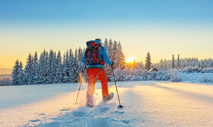 un homme marchant avec des raquettes dans la neige