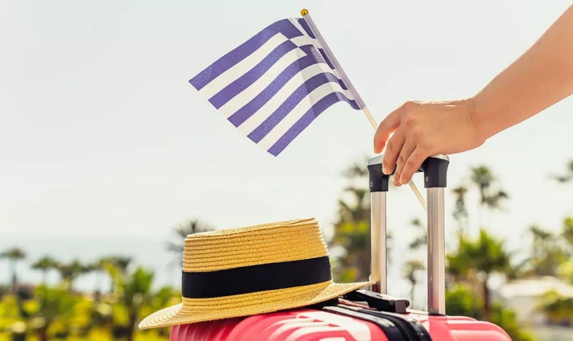 un drapeau grec et un chapeau de paille sur une valise