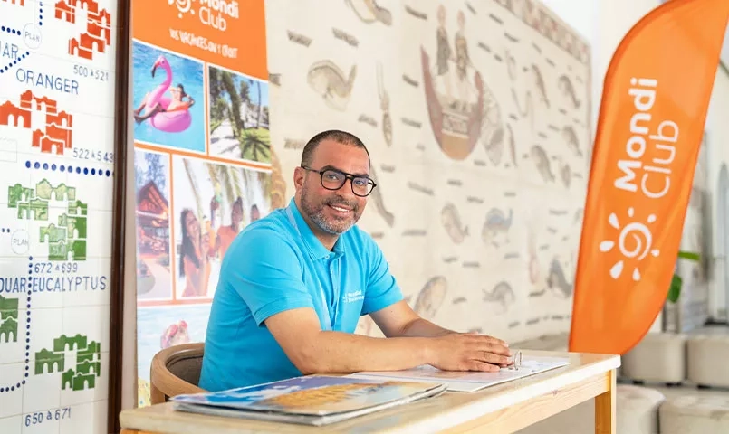 Un homme souriant devant une bannière "Mondi Club" .