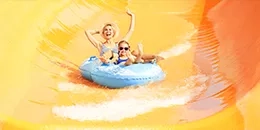 2 enfants sur une bouée dans un toboggan jaune