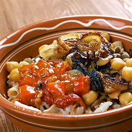Koshari égyptien, plat de rue à base de riz, lentilles, pois chiches, oignons frits et sauce tomate épicée.