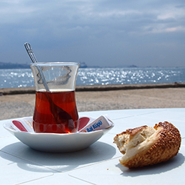 Thé turc servi dans un verre tulipe, moment de pause convivial face à la mer 